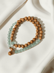 Barbie Agarwood & Jade Pendant Necklace styled on soft white fabric, featuring soothing green jade and light agarwood beads, a mindful accessory for off-mode calm and emotional reset.