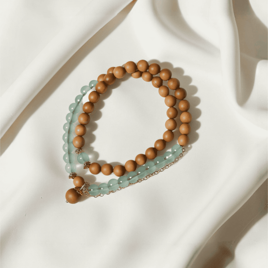 Barbie Agarwood & Jade Pendant Necklace styled on soft white fabric, featuring soothing green jade and light agarwood beads, a mindful accessory for off-mode calm and emotional reset.