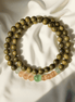 Green Sandalwood & Cat’s Eye Buddha Bracelet laid on soft ivory fabric, featuring warm wood tones and calming gemstone accents, ideal for emotional reset in off-mode evening rituals.